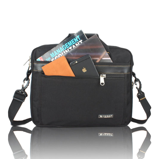 Black shoulder bag with compartments containing a phone, books, and an orange card on a reflective surface.
